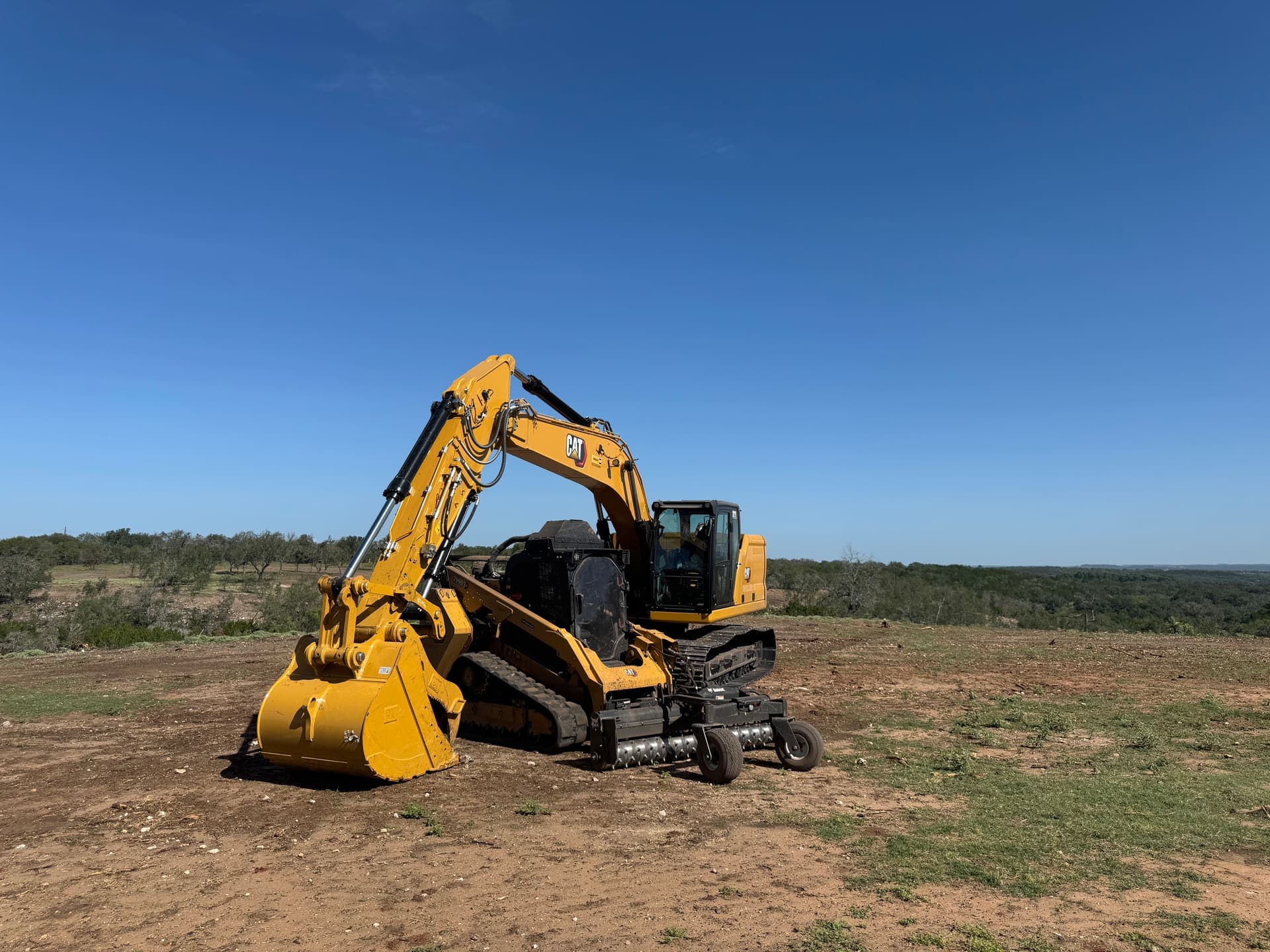 Grounded Land Services CAT excavator on cleared Texas land